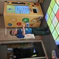 Photograph of a faculty member instructing an immersive game about volcanic eruptions. He is stood behind a set of large floor panels which are lit up in different colours.