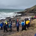 Photograph of students stood on a rocky beach wearing outdoor gear