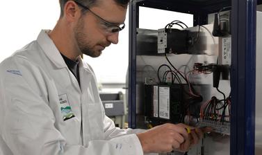 Workshop manager using a screwdriver to change the wiring in a partly constructed piece of machinery