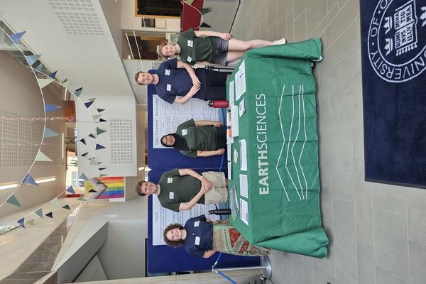 Photograph of open day volunteers standing at the welcome desk during a departmental open day.