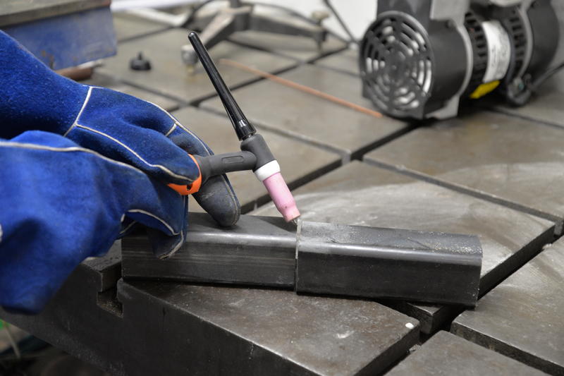 Workshop worker welding two pieces of metal tube together