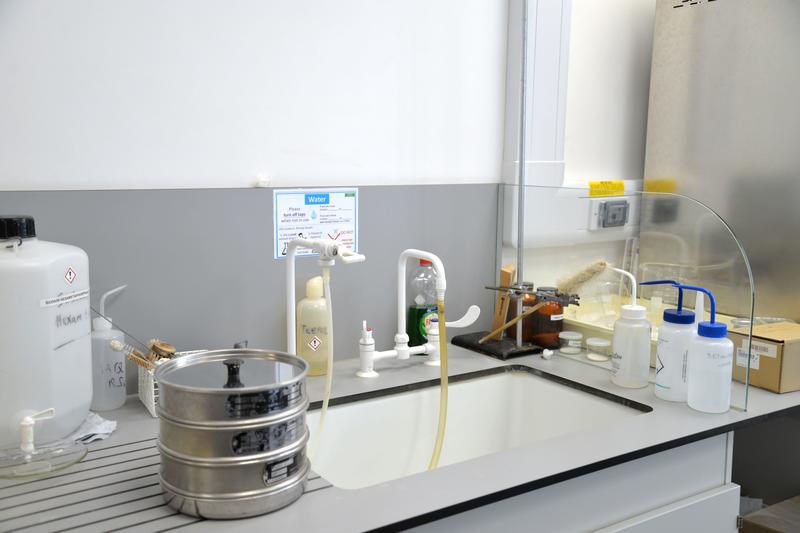 Bottles, hoses, sieves, and sample containers arranged around a laboratory sink.