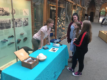Photograph of Erin Saupe talking to members of the public at a display in a museum