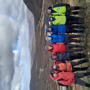 Demonstrators on the Assynt Field Class 2 Group photo of demonstrators on the Assynt field course. They are wearing outdoor gear and are smiling at the camera with their arms wrapped around each other.